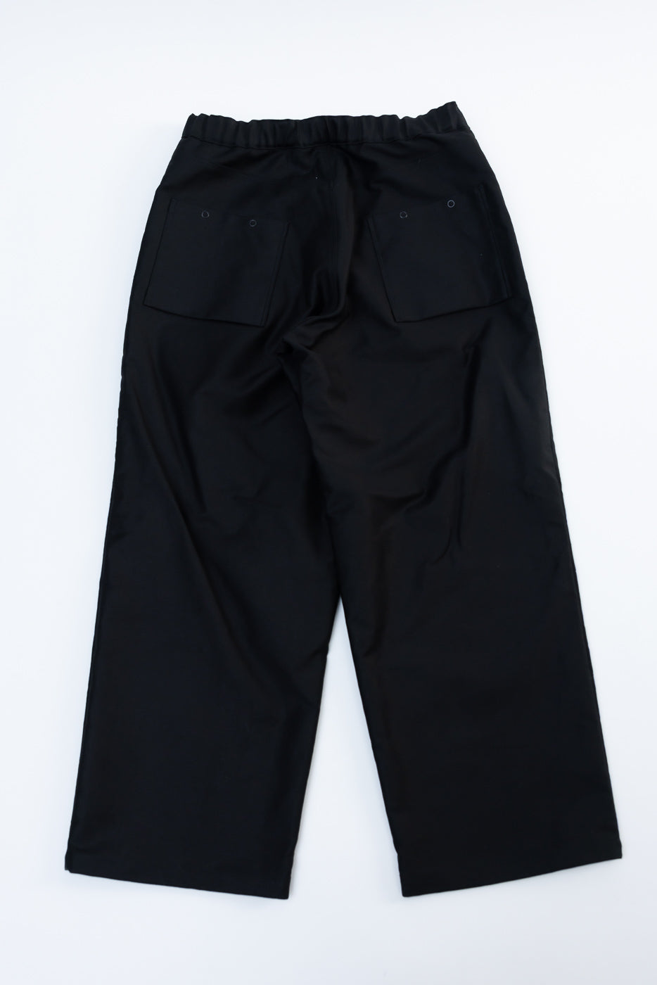 Flat lay of baggy black moleskin trousers, back view showing elastic waistband and rear patch pockets