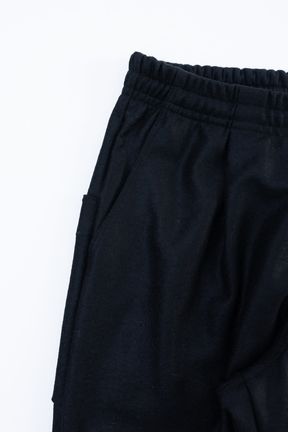 Close-up of front left side of black wool moleskin trouser, showing waistband and pocket detail.