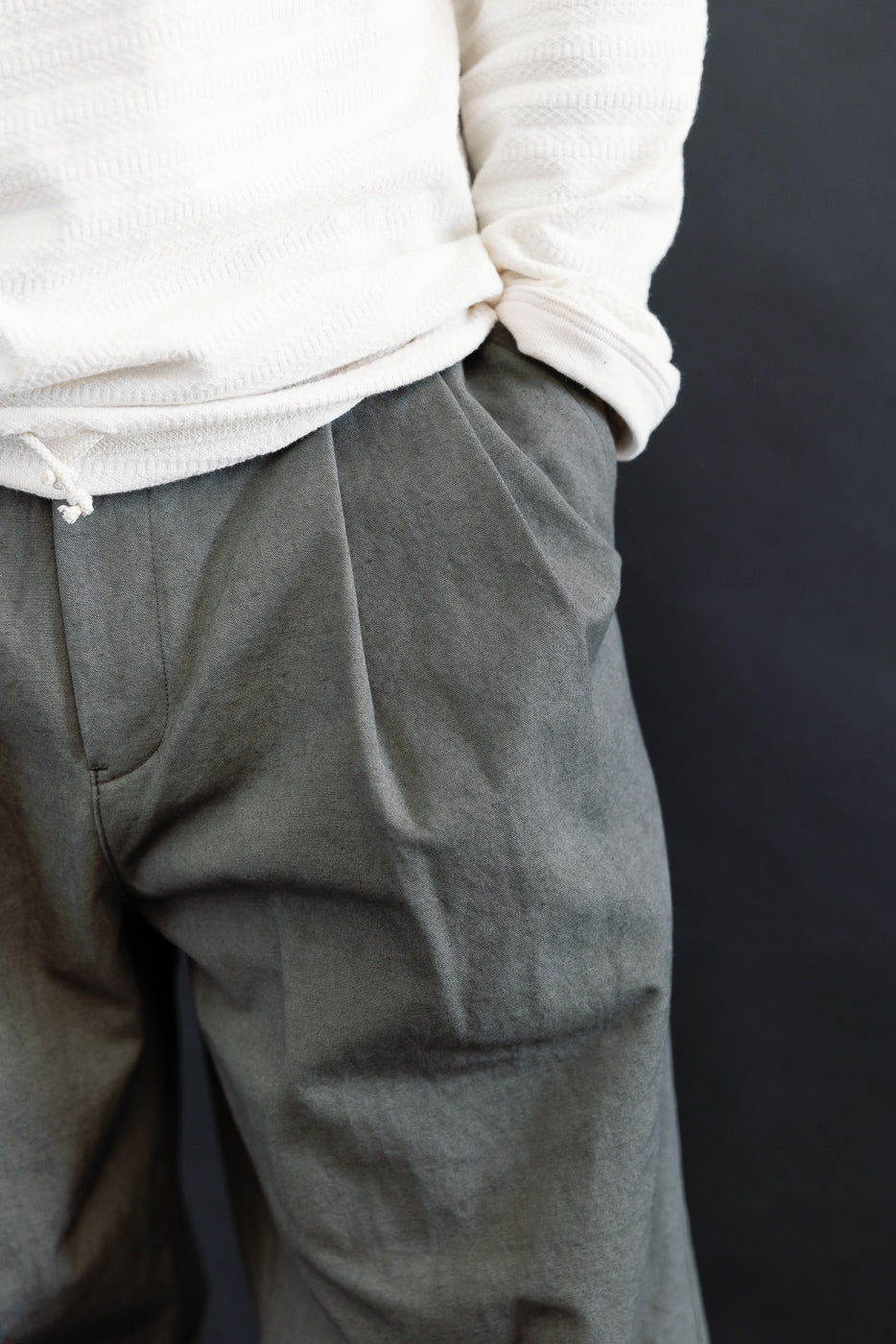 Close-up front view of dark moss gray canvas trousers on male model, 5'9