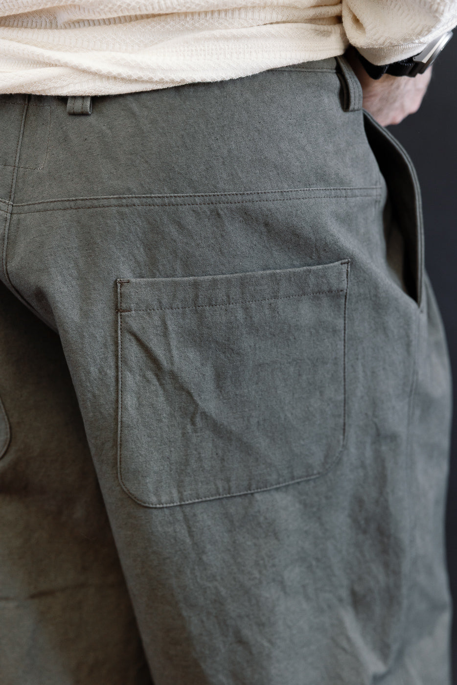 Close-up of back pocket on men's dark moss gray canvas trousers, male model 5'9 165lbs athletic build