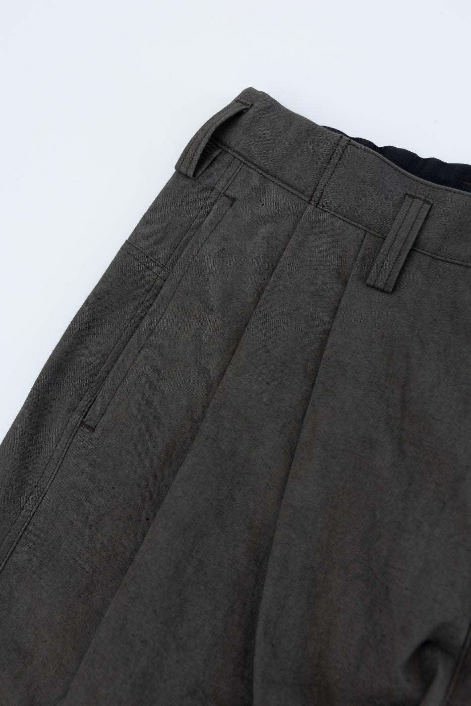 Close-up of back side of dark moss gray canvas trousers, showing waistband, belt loops, and pocket detail