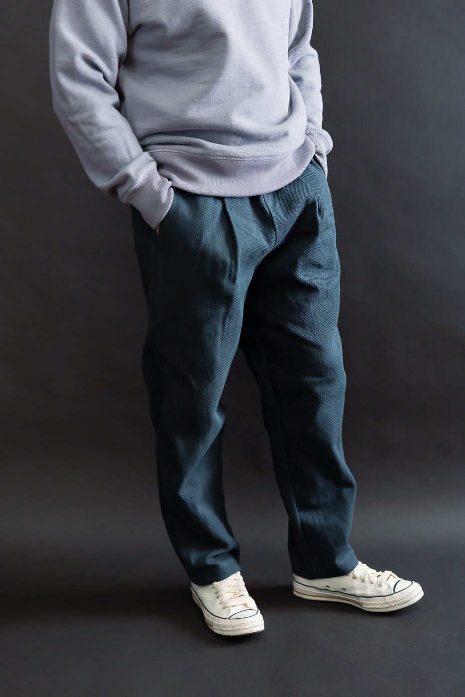 JM4623 - Sashiko Ump Pants - 280 Iron Navy shown on lower half, featuring a pleated front and large pocket, styled with off-white sneakers, highlighting the pants' structured, denim-like drape and utilitarian design.