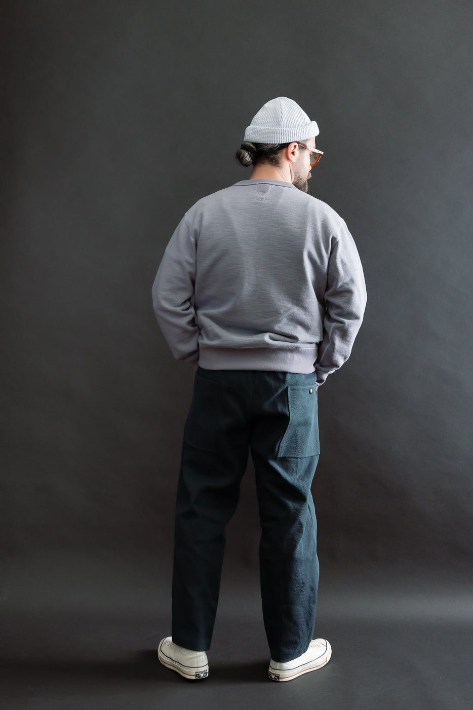 JM4623 - Sashiko Ump Pants - 280 Iron Navy: A man models these dark utility trousers with large side pockets, showcasing their structured drape and minimalistic, workwear-inspired style.