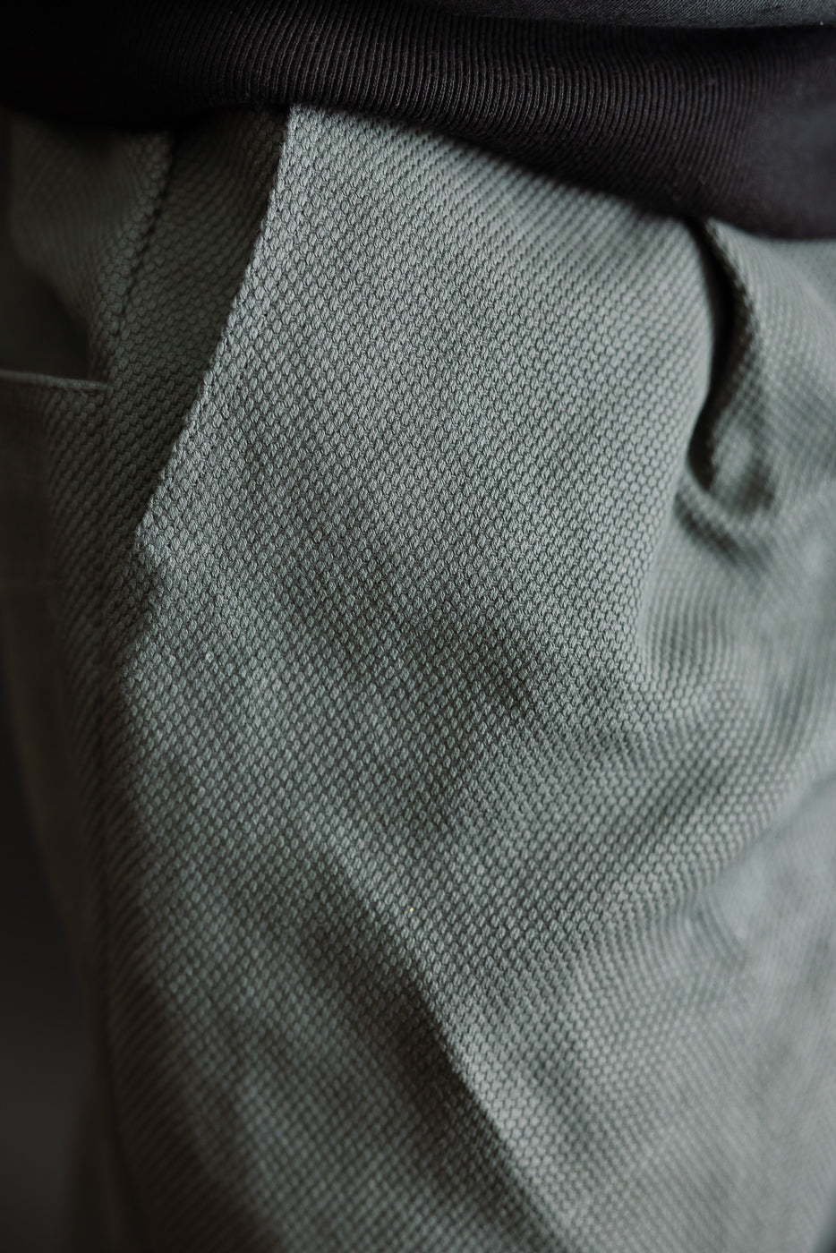 JM4623 - Sashiko Ump Pants in a textured green fabric, showcasing a visible side pocket and hem of a black shirt, highlighting the unique, structured sashiko fabric akin to raw denim.