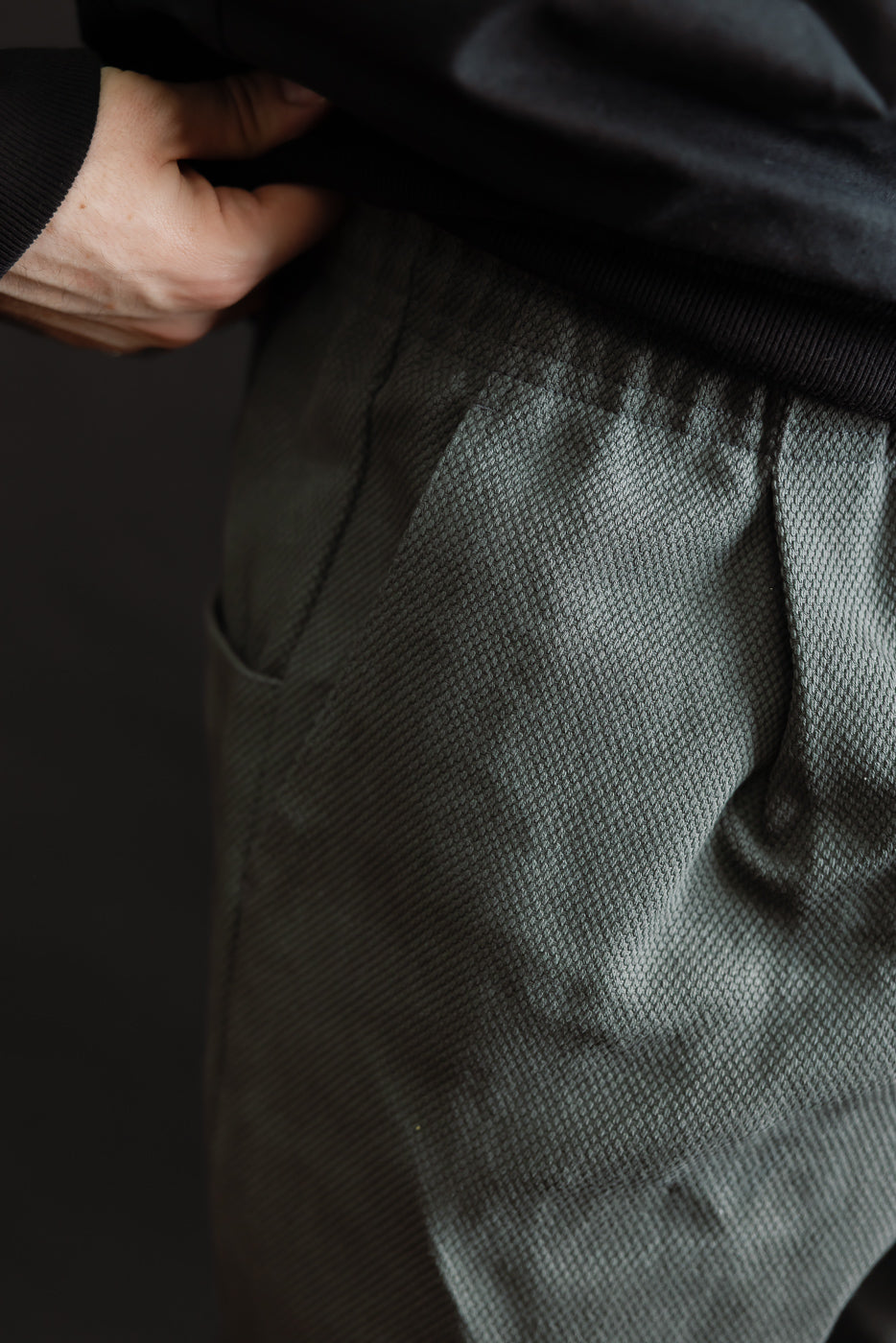 JM4623 - Sashiko Ump Pants feature a textured sashiko fabric with an elastic waistband, pleated front, and large hip pocket, reflecting a workwear-inspired design.