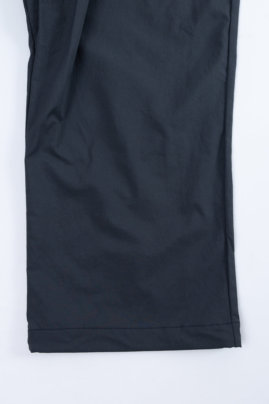 Close-up of dark navy pants front, showing clean hem and smooth fabric texture