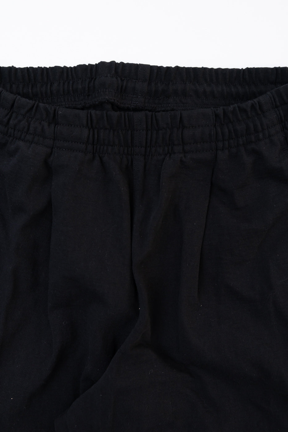Close-up of the elastic waistband and fabric texture on the front of black casual trousers.