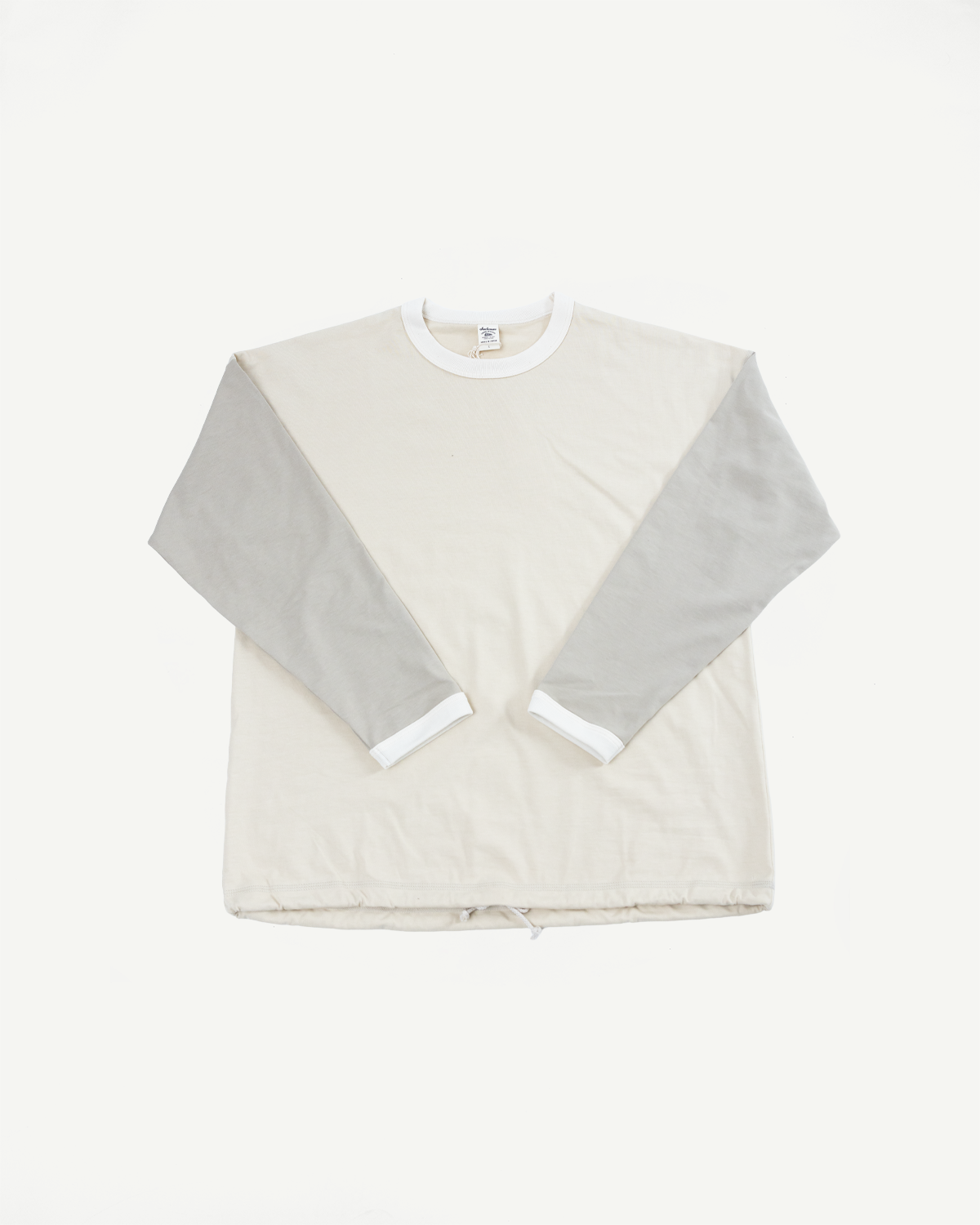 Front flat lay of cream long-sleeve shirt with gray sleeves, white ribbed collar, and drawstring hem.
