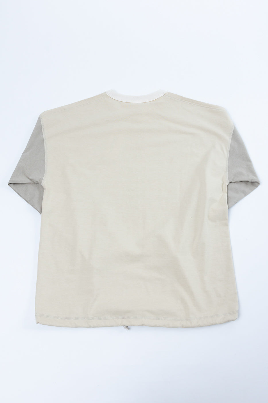 Back view of beige t-shirt with gray sleeves, flat lay, showing hem and stitching details