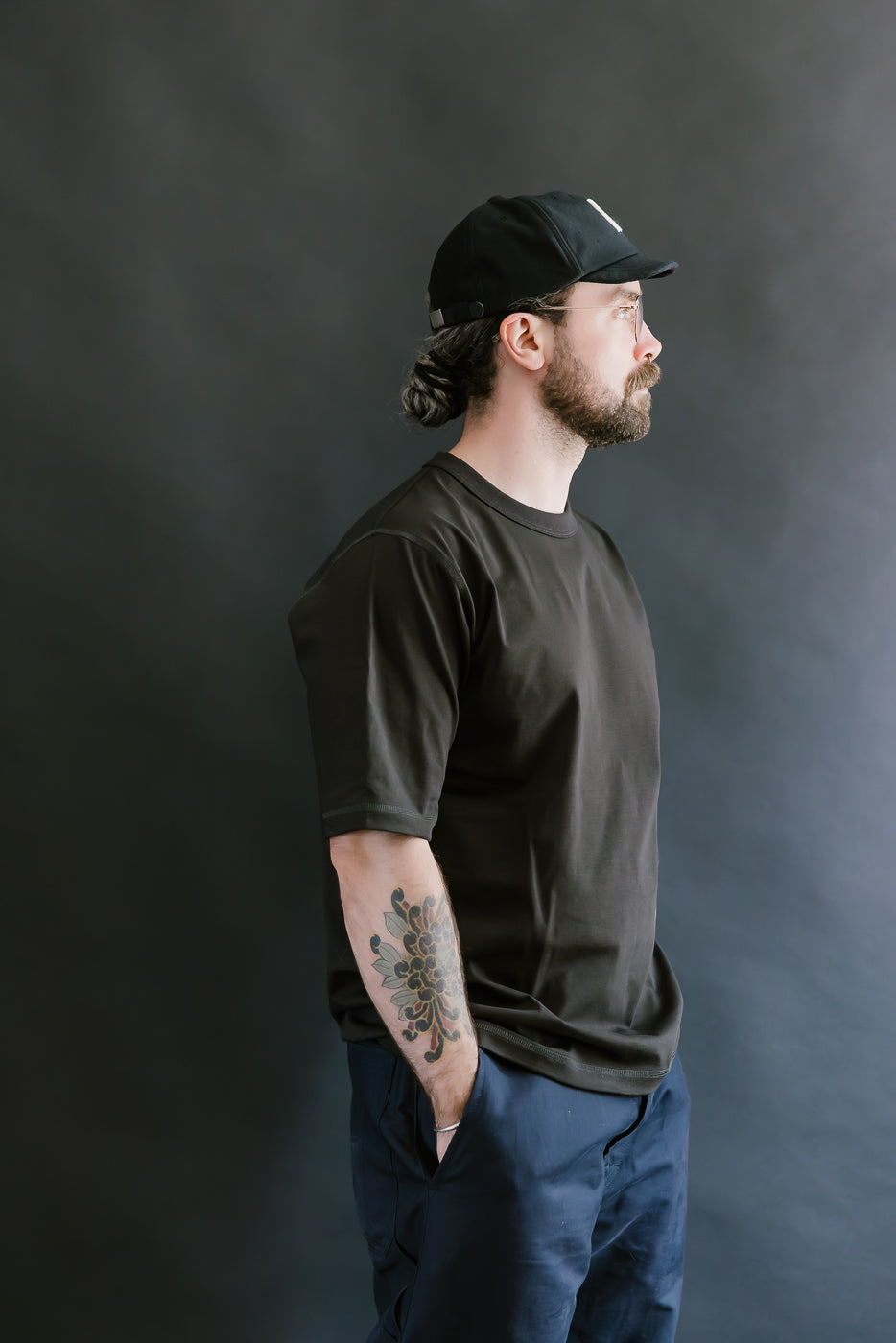 Man wearing a black t-shirt and cap against a dark background