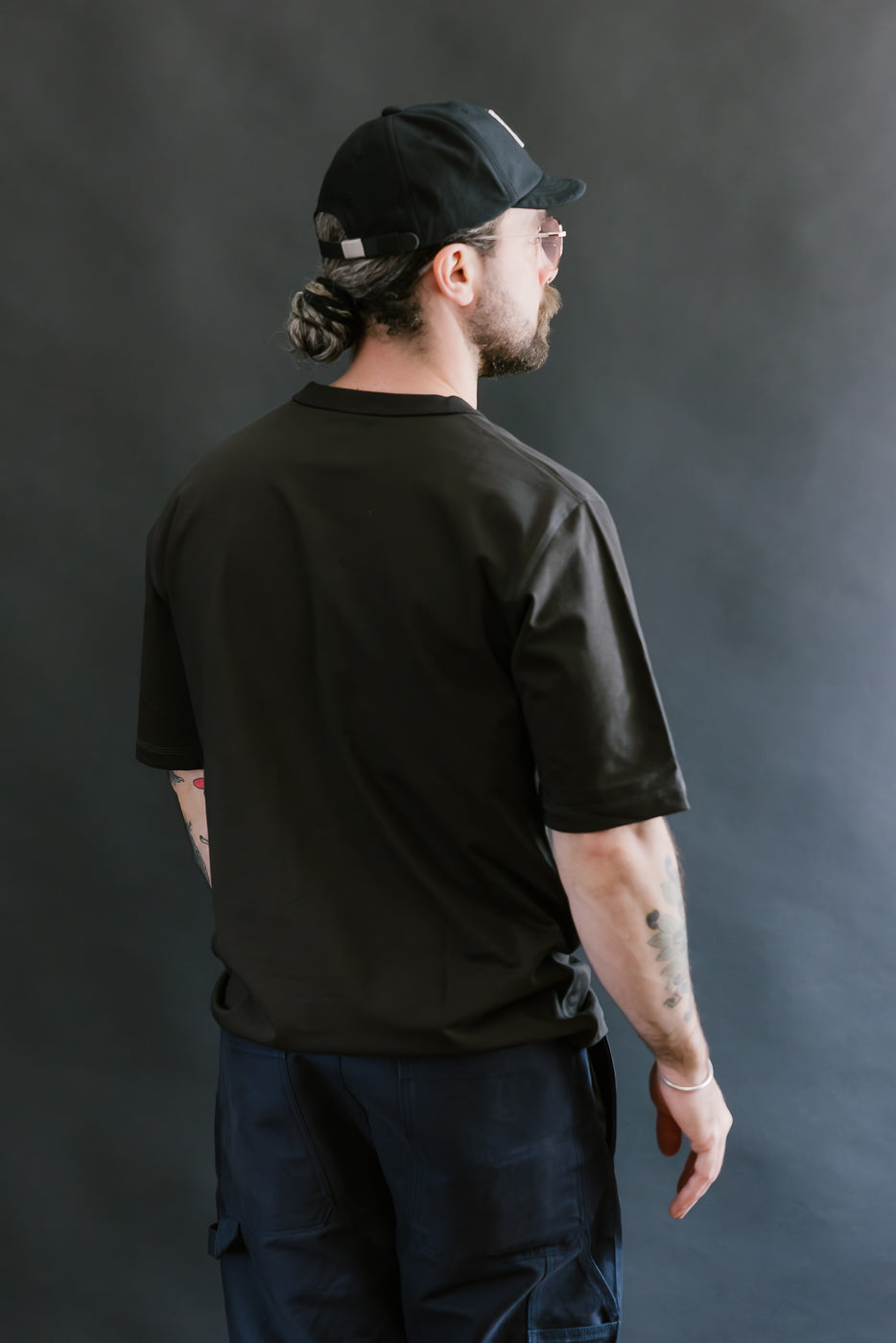 Man wearing a black t-shirt and cap against a dark background