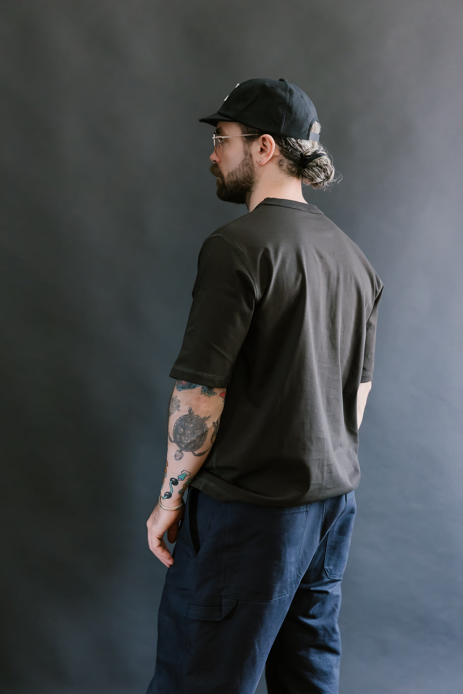 Man wearing a black t-shirt and cap against a gray background