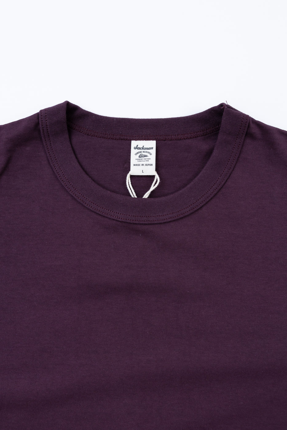 Close-up of a purple t-shirt with a brand label on a white background