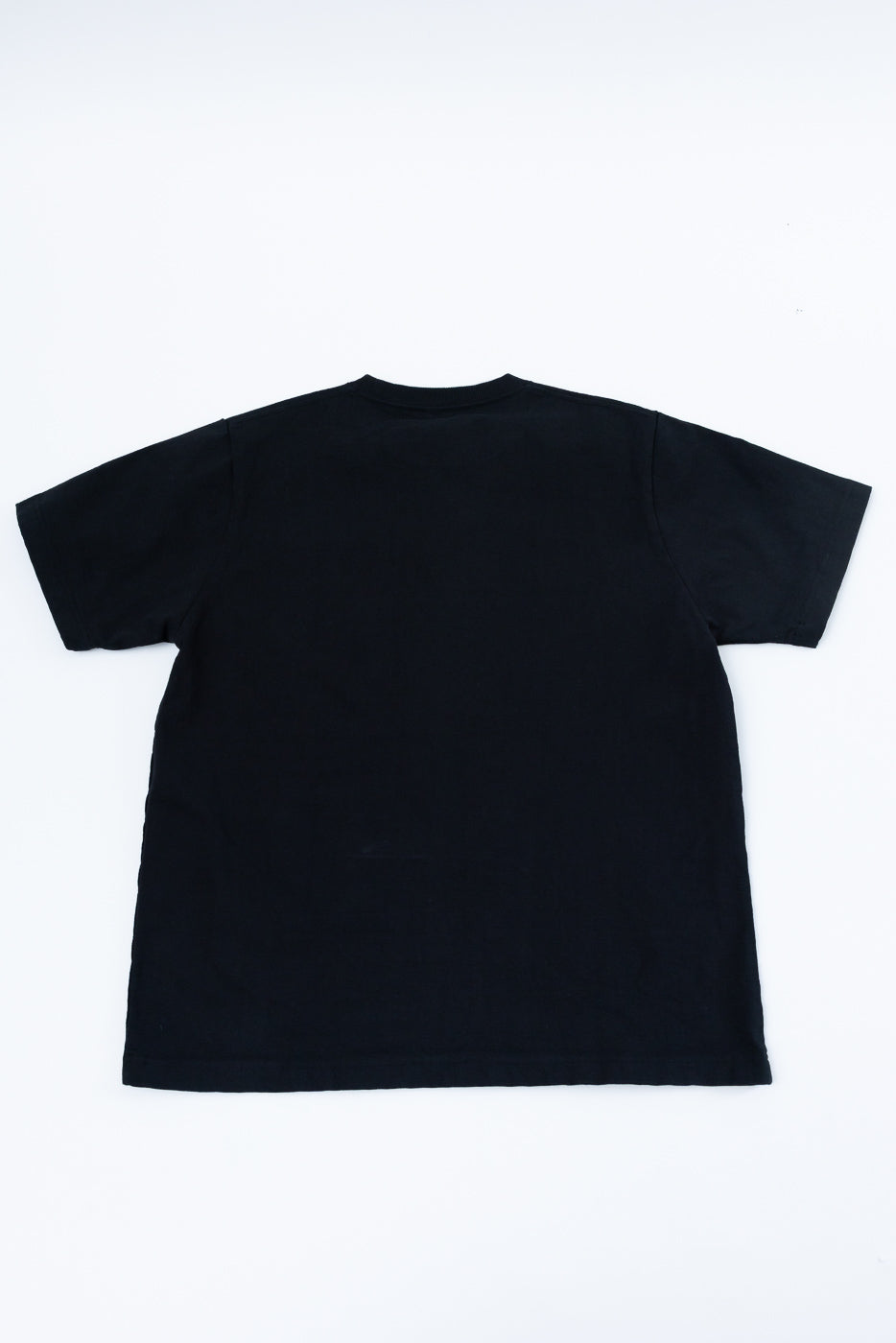 Black crewneck t-shirt back view, flat lay, showing hem and sleeve details