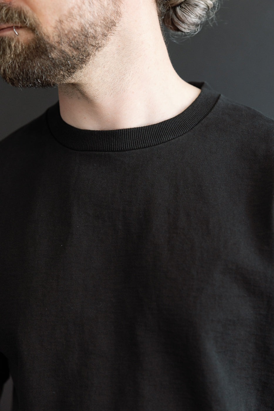 Close-up front view of black crewneck tee on male model, 5'9