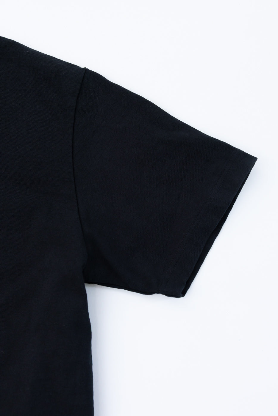 Close-up of black t-shirt sleeve hem, showing clean stitching and fabric texture, front view