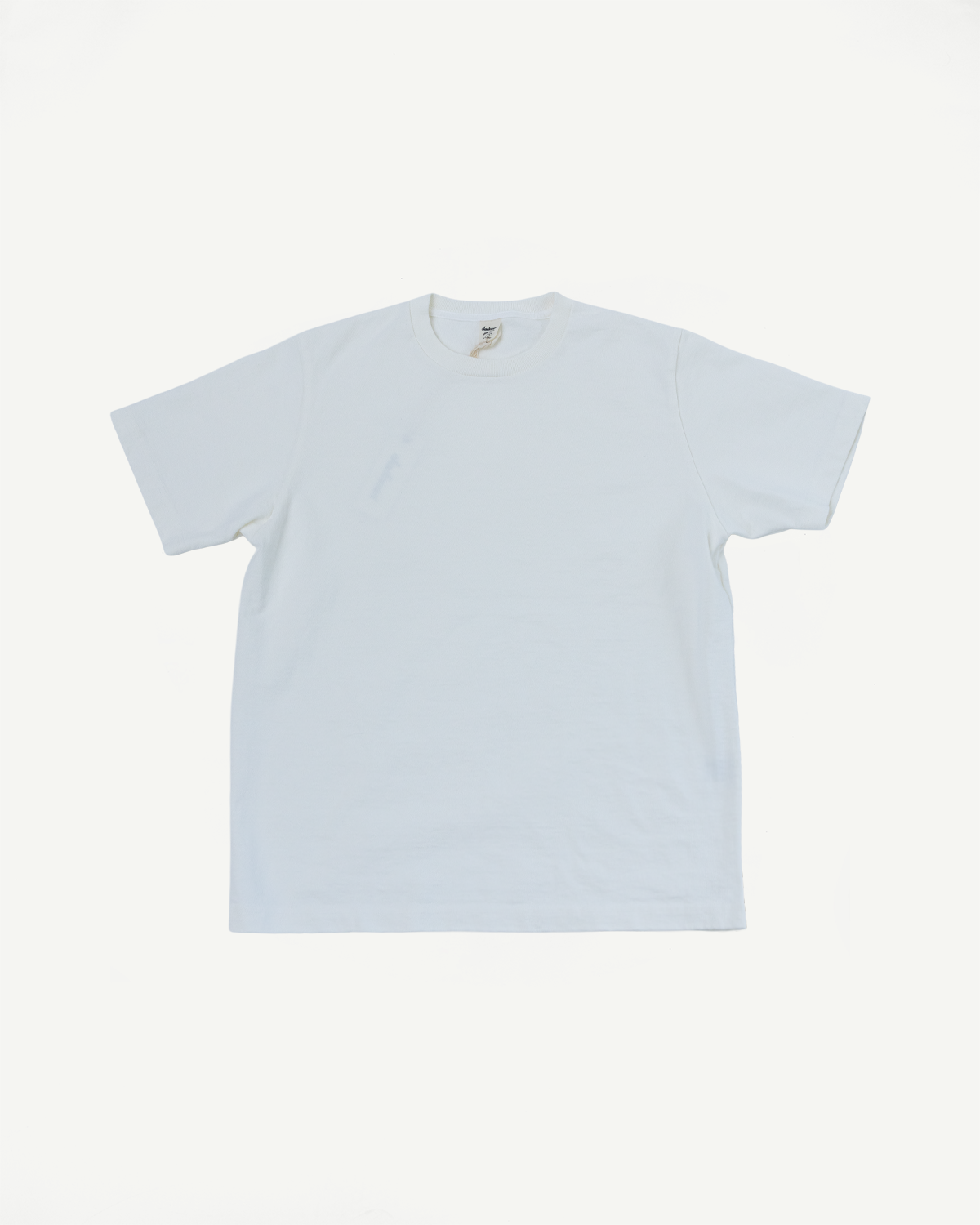 White crewneck t-shirt flat lay, front view, showing tag detail and clean hem