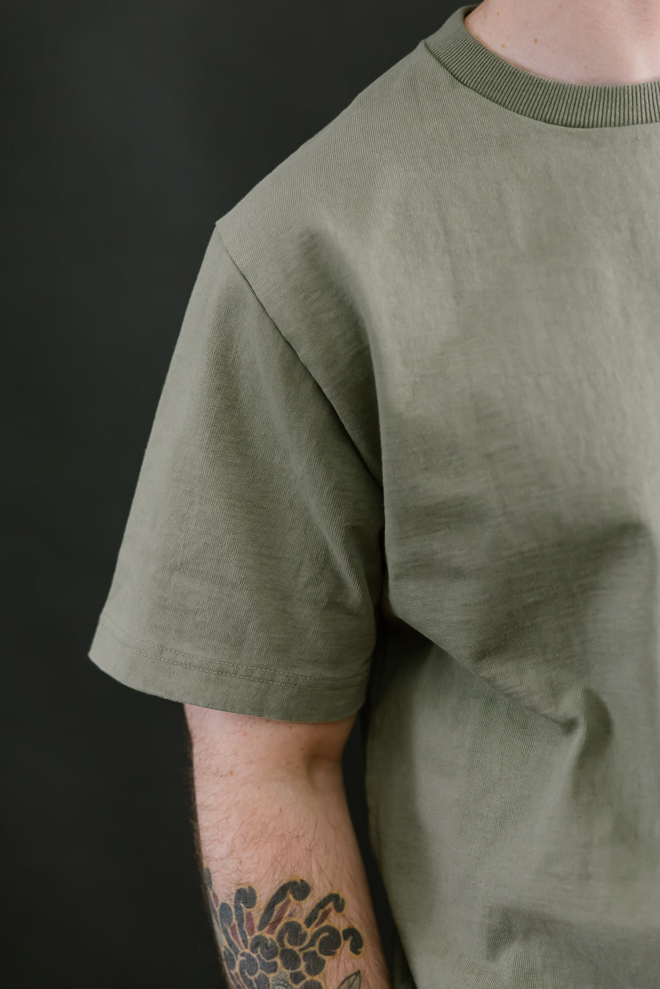 Person wearing a green t-shirt against a black background