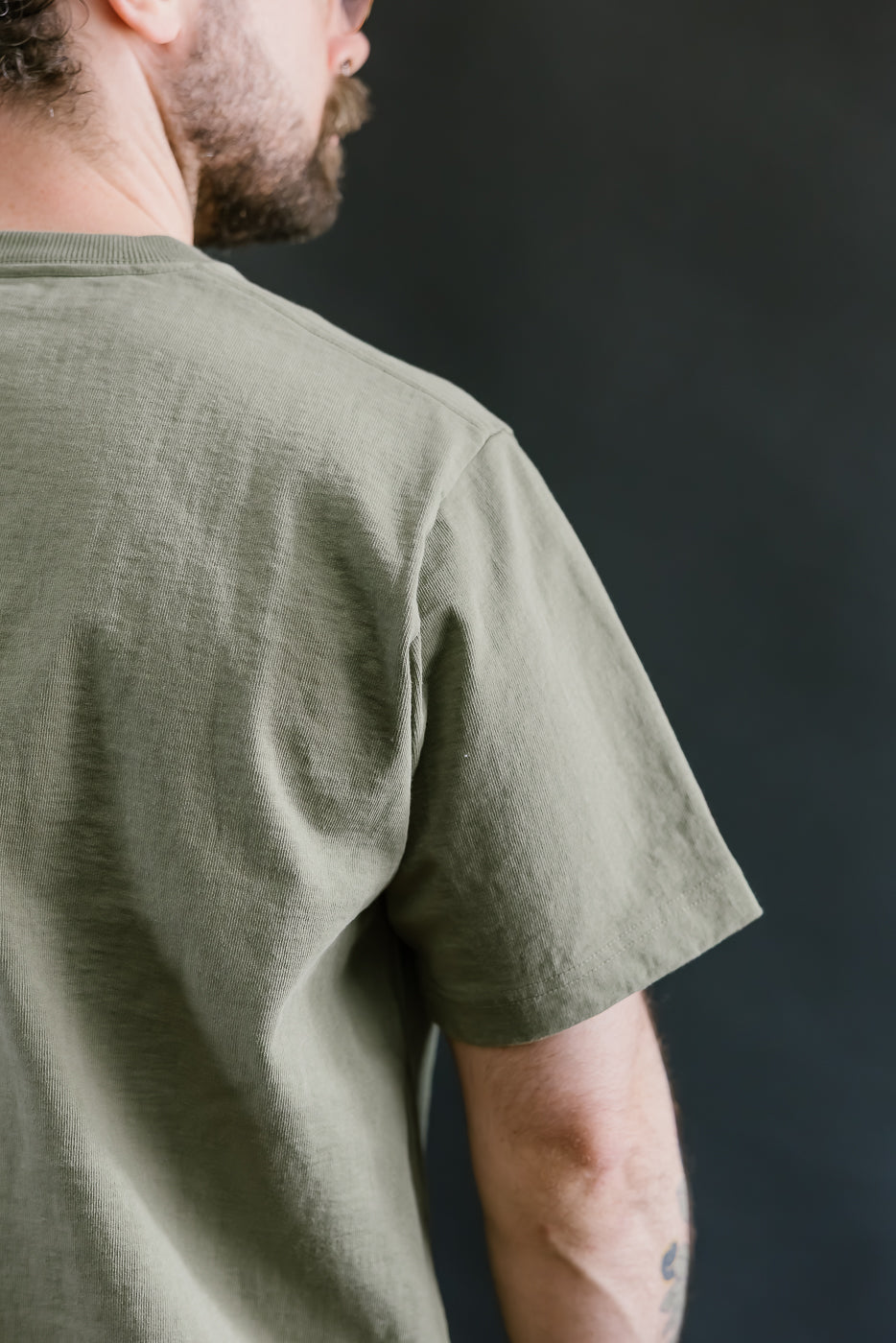 Person wearing a green t-shirt against a dark background