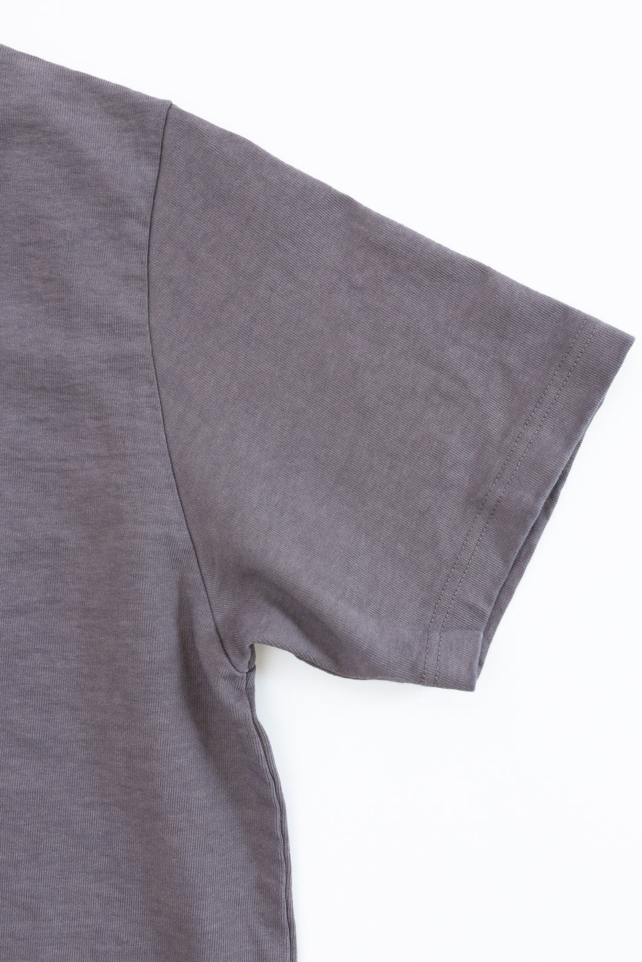 Close-up front view of dark gray short-sleeve tee showing sleeve hem, shoulder seam, and fabric texture