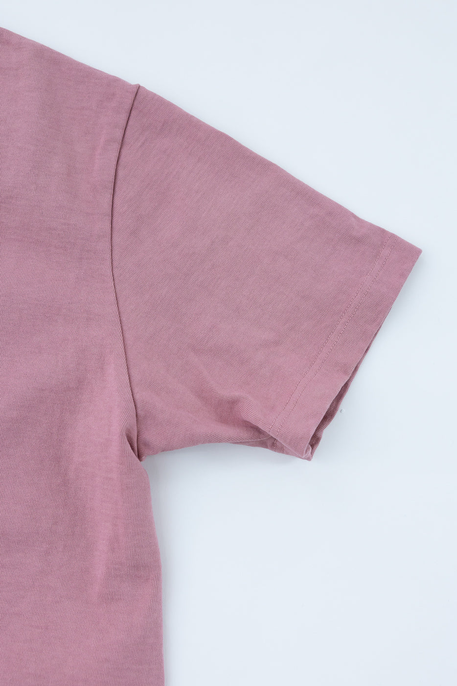 Close-up of dusty rose t-shirt sleeve, showcasing ribbed texture and clean hem detail