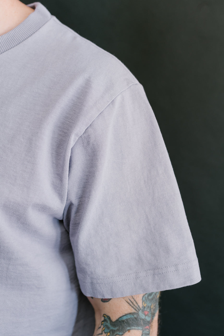 shoulder seam of the light purple shirt with sleeve hitting just above the elbow