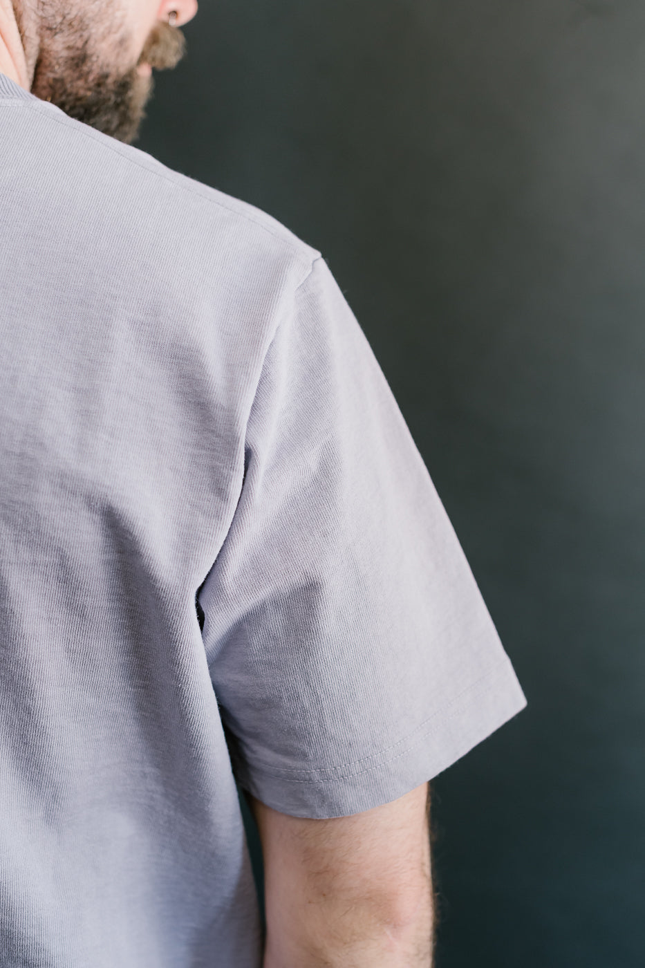 back shoulder seam of light purple shirt with length hitting directly above the elbow
