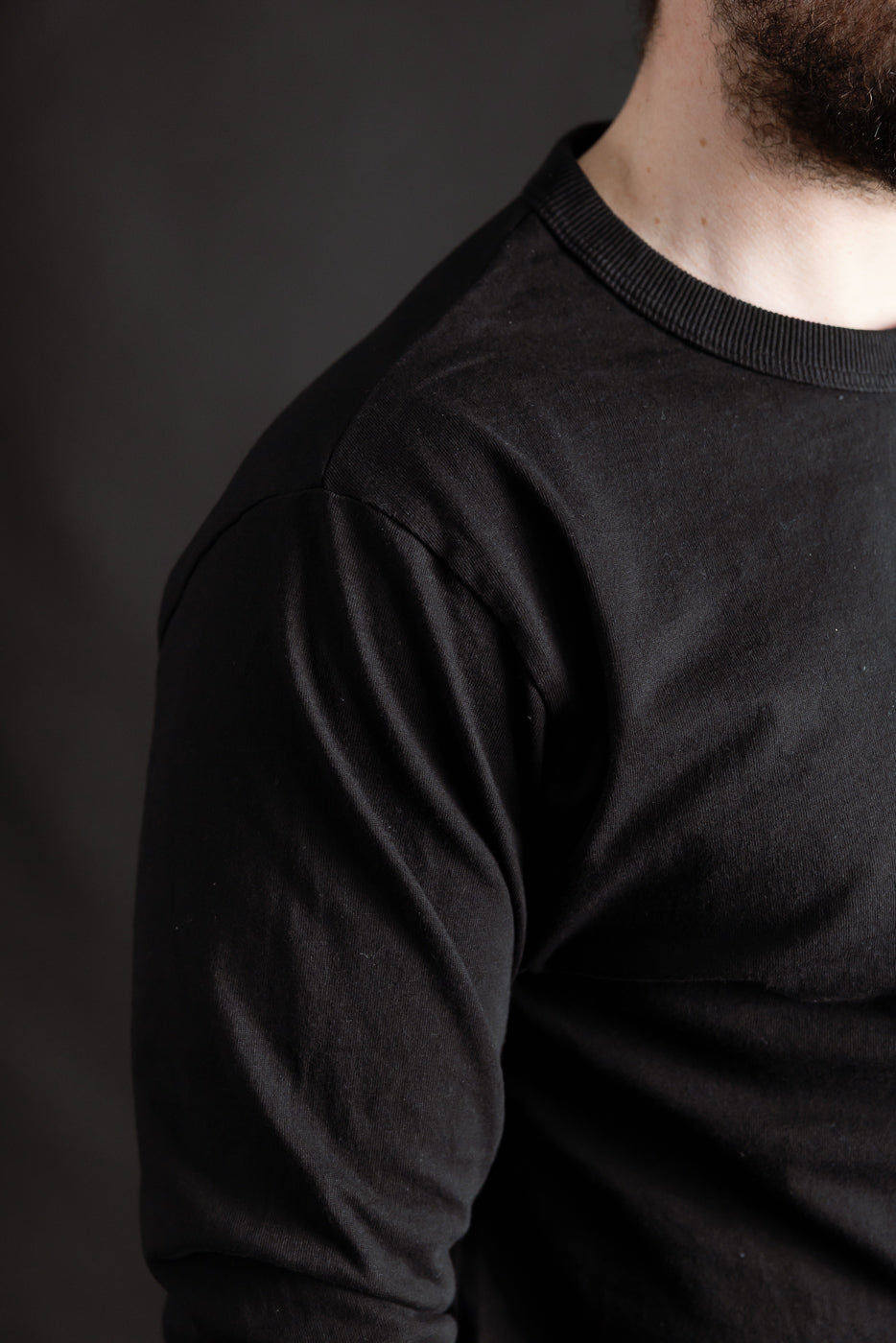 Close-up of front right shoulder and chest of black Jackman T-shirt on male model, 5'9