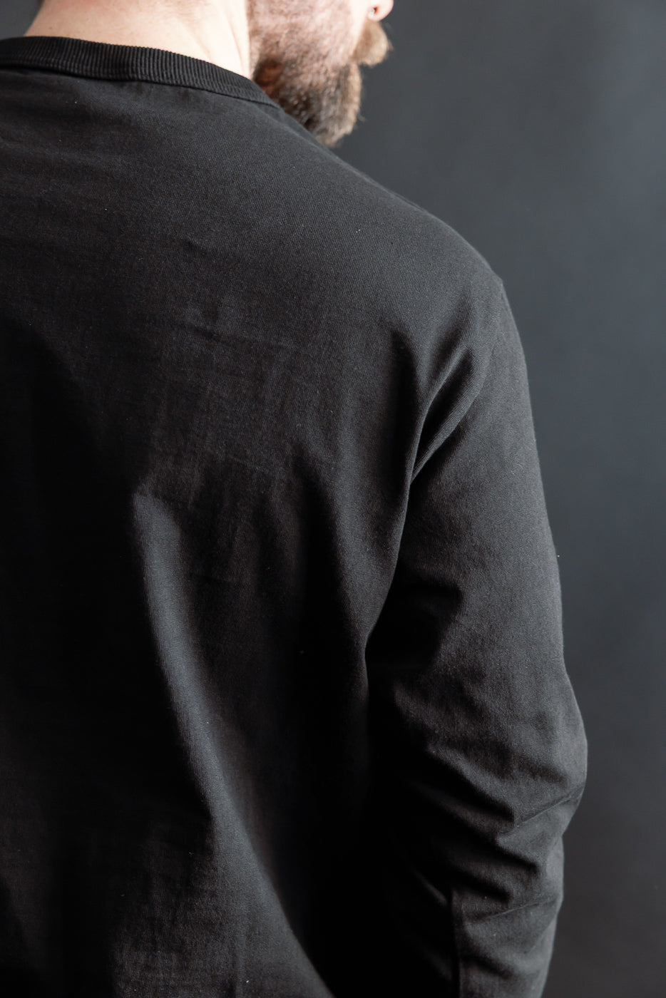 Close-up of back upper detail, black lead-off t-shirt on male model, athletic build, Dant