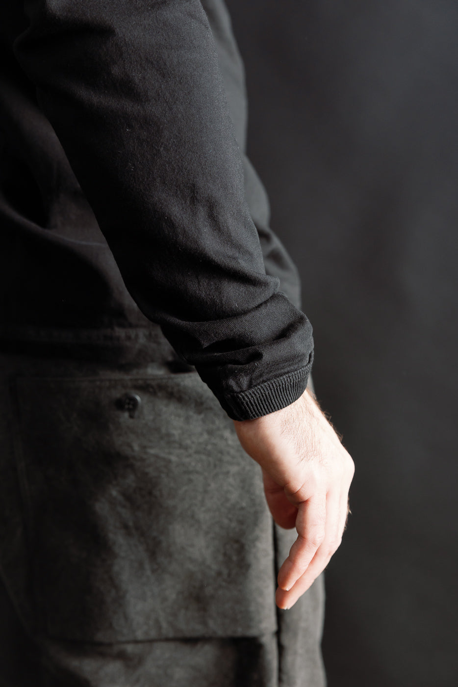 Close-up of Jackman black long sleeve t-shirt cuff on male model, left side view, athletic build