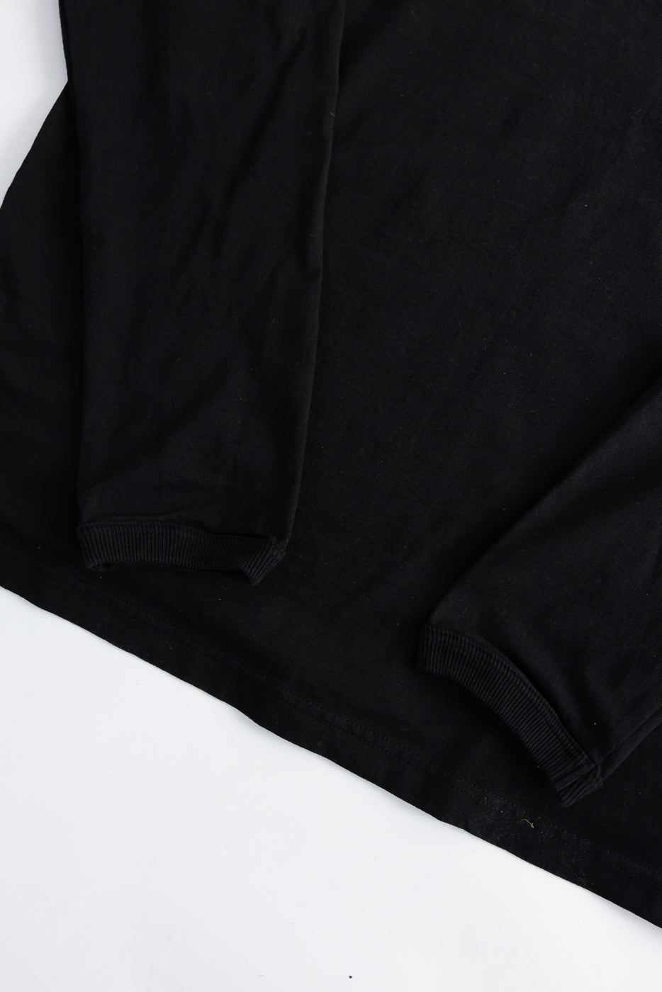 Close-up of black long sleeve t-shirt cuffs and hem, flat lay, front side, ribbed details