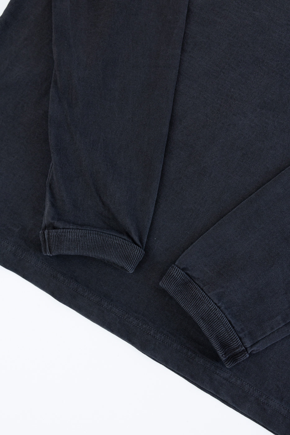 Close-up of dark long-sleeve shirt's ribbed cuffs and hem, front view