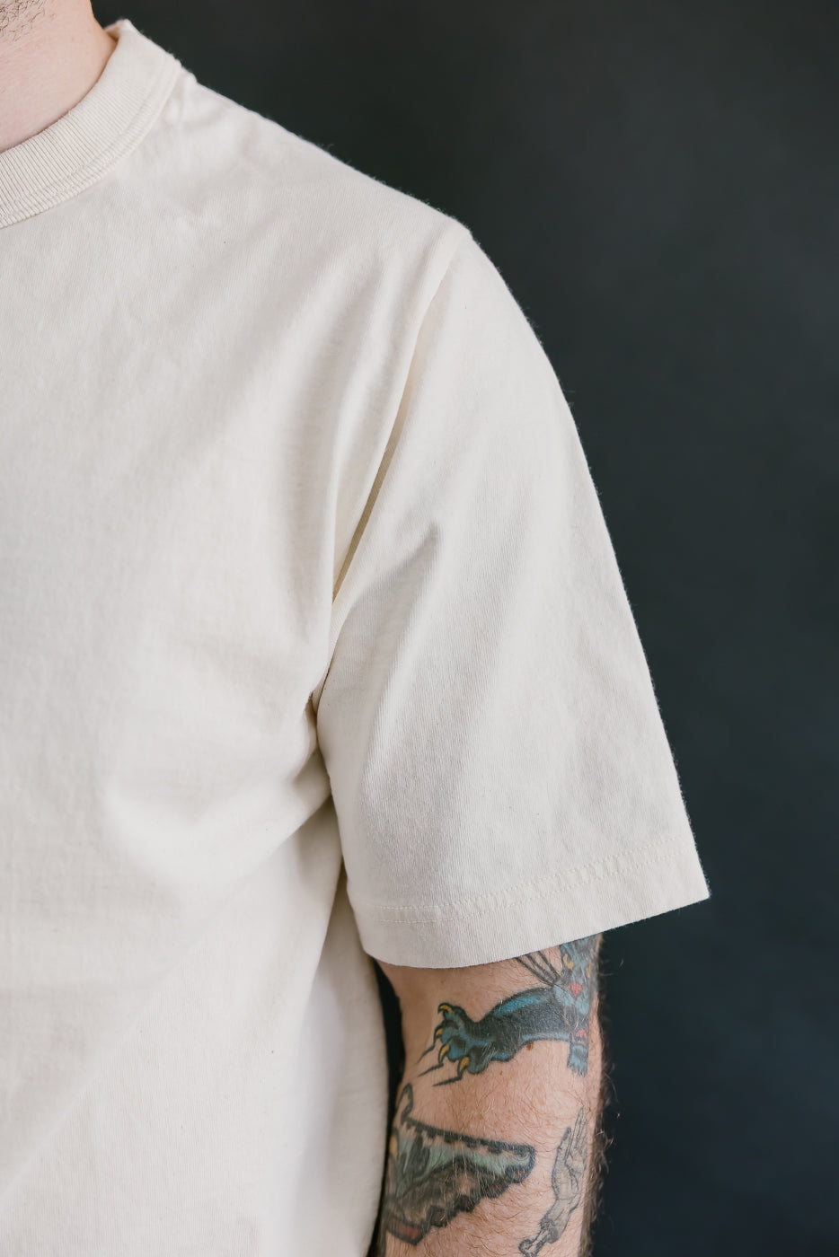 Person wearing a beige t-shirt with a dark background