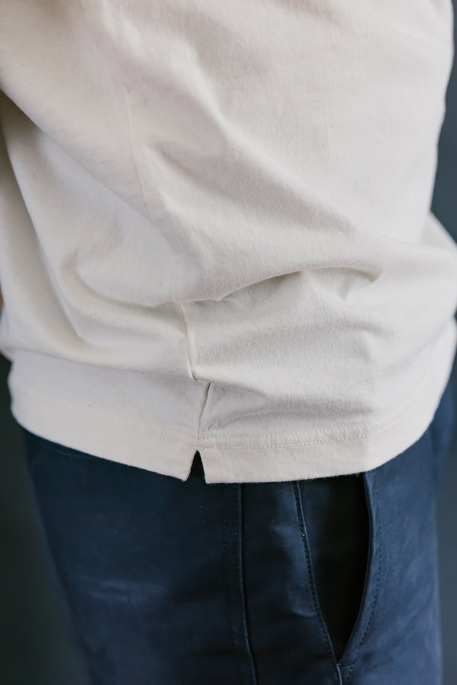 Close-up of a person wearing a light-colored shirt and dark pants.