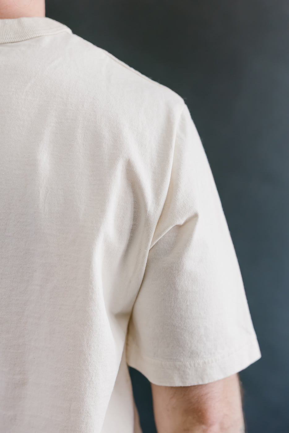 Person wearing a beige shirt against a dark background