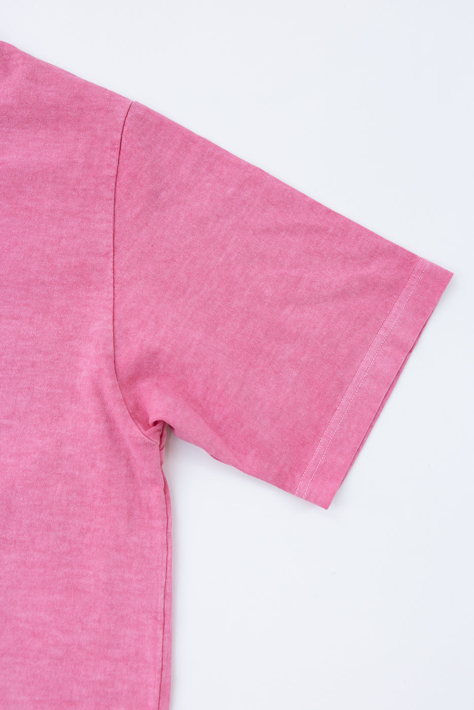 Close-up of pink t-shirt sleeve, showing hem and fabric texture, front view
