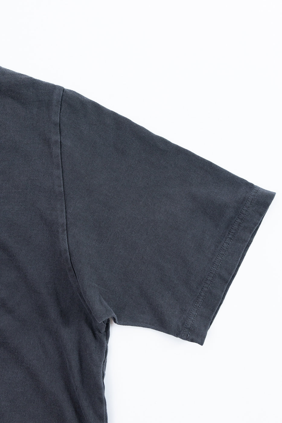Close-up of dark gray t-shirt sleeve and shoulder seam, showing fabric texture and stitching detail