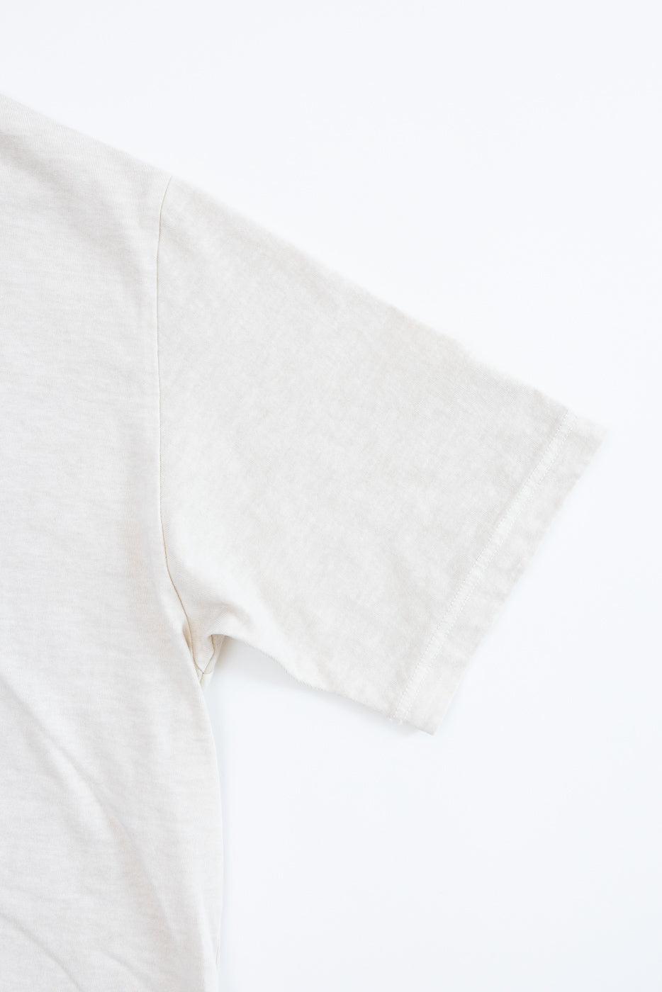 Close-up of cream t-shirt sleeve, showing hem and fabric texture