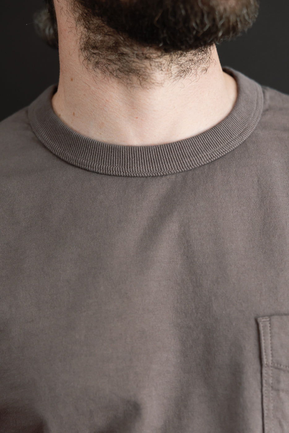 Close-up front view of a male model's neck and crew neck t-shirt with ribbed collar and chest pocket