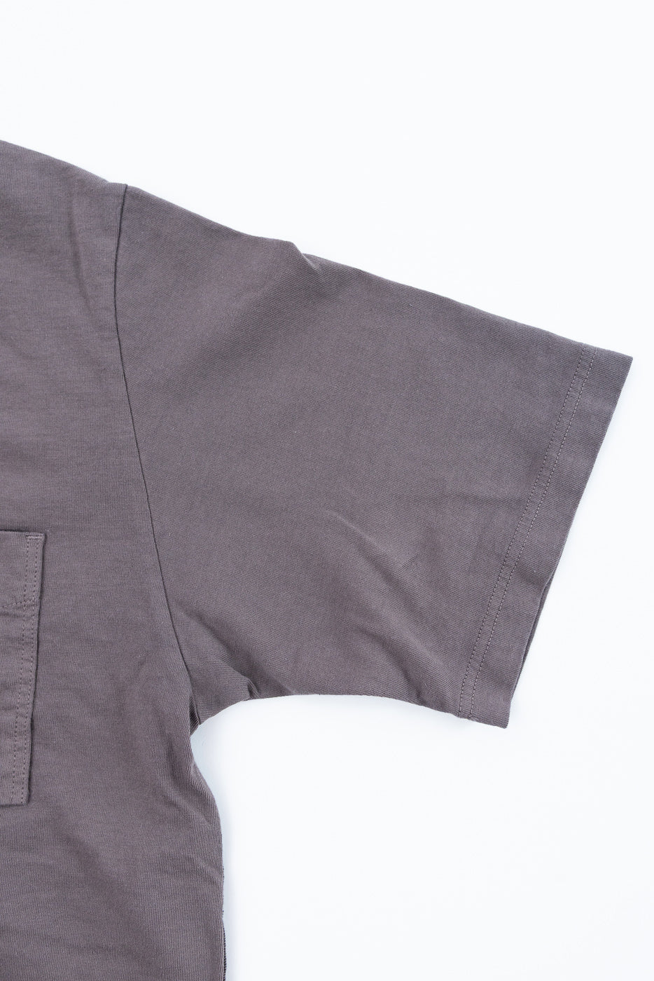 Close-up front view of charcoal gray short-sleeve shirt showing sleeve hem, chest pocket, and fabric texture
