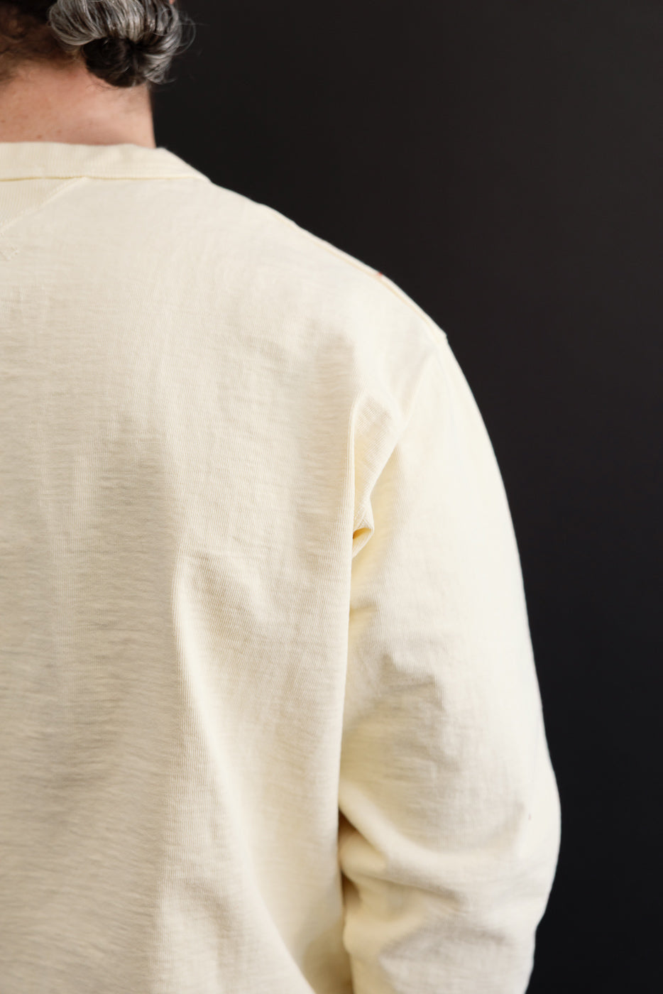 Close-up back view of a cream long-sleeve cotton shirt showing fabric texture.