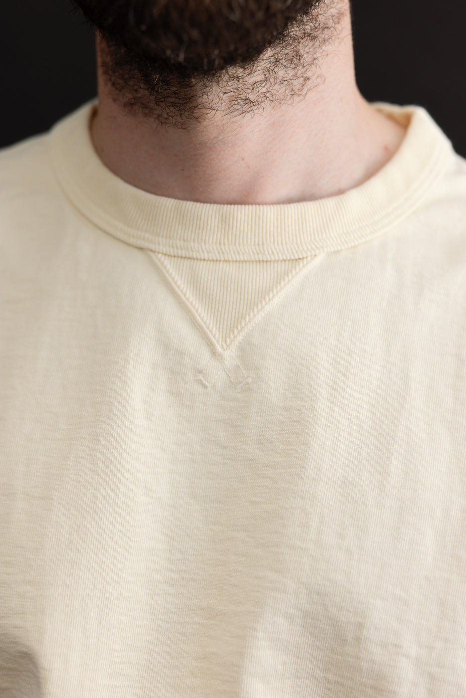 Close-up front view of a cream sweatshirt collar and ribbed neckline detail.