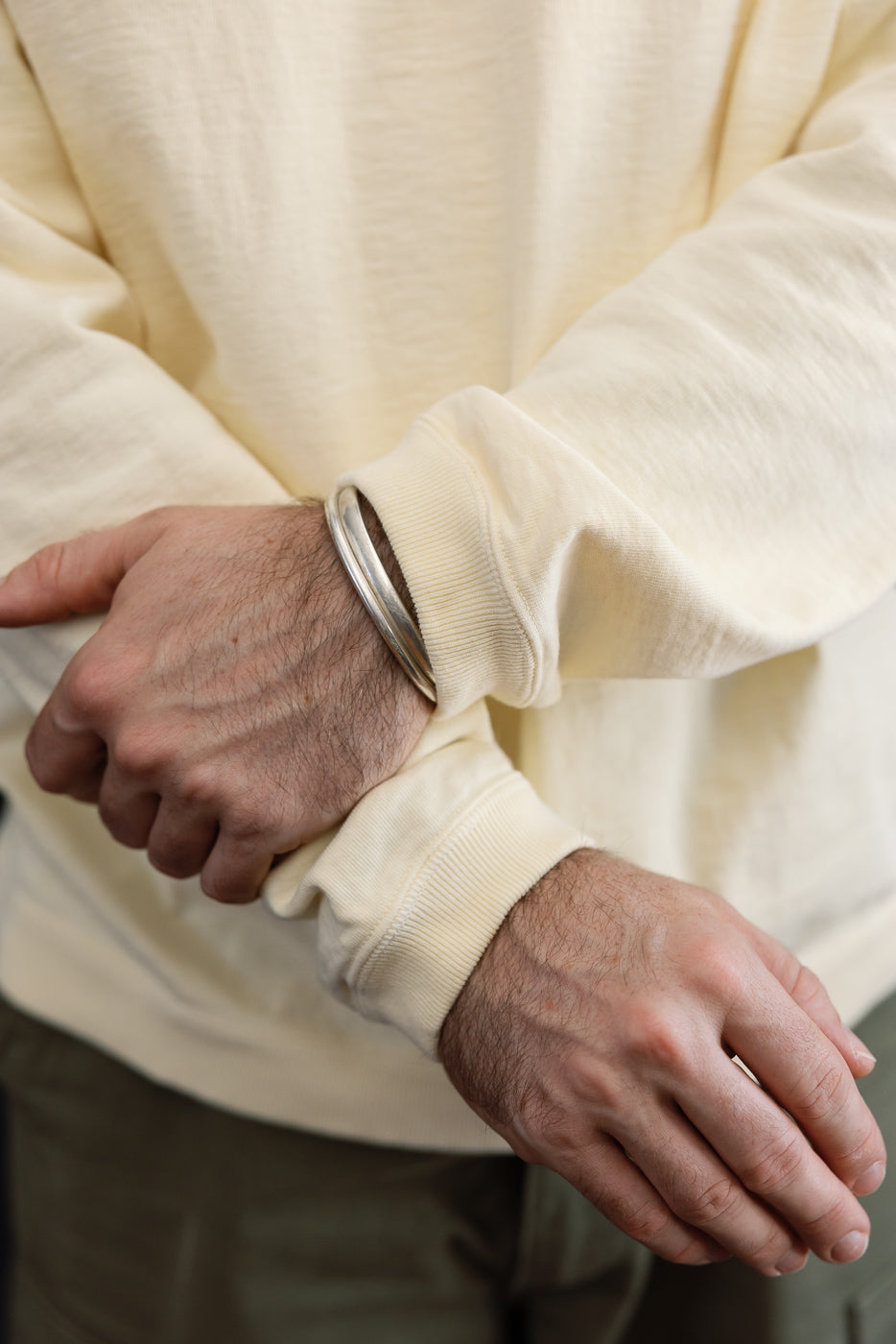 Close-up of the ribbed cream sweatshirt cuff and sleeve detail on a male model.