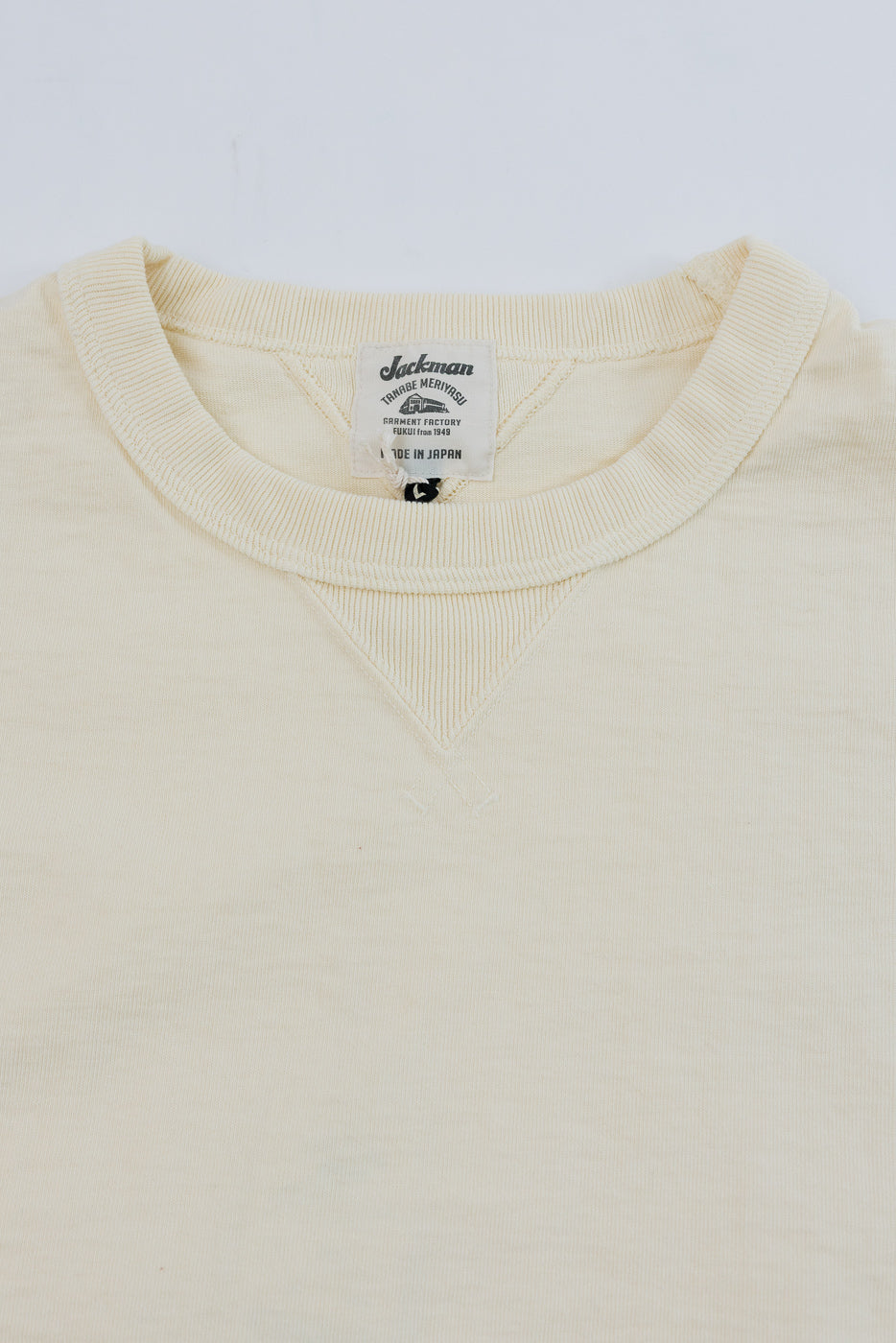 Close-up of the front neckline and Jackman brand tag on a cream thermal shirt.