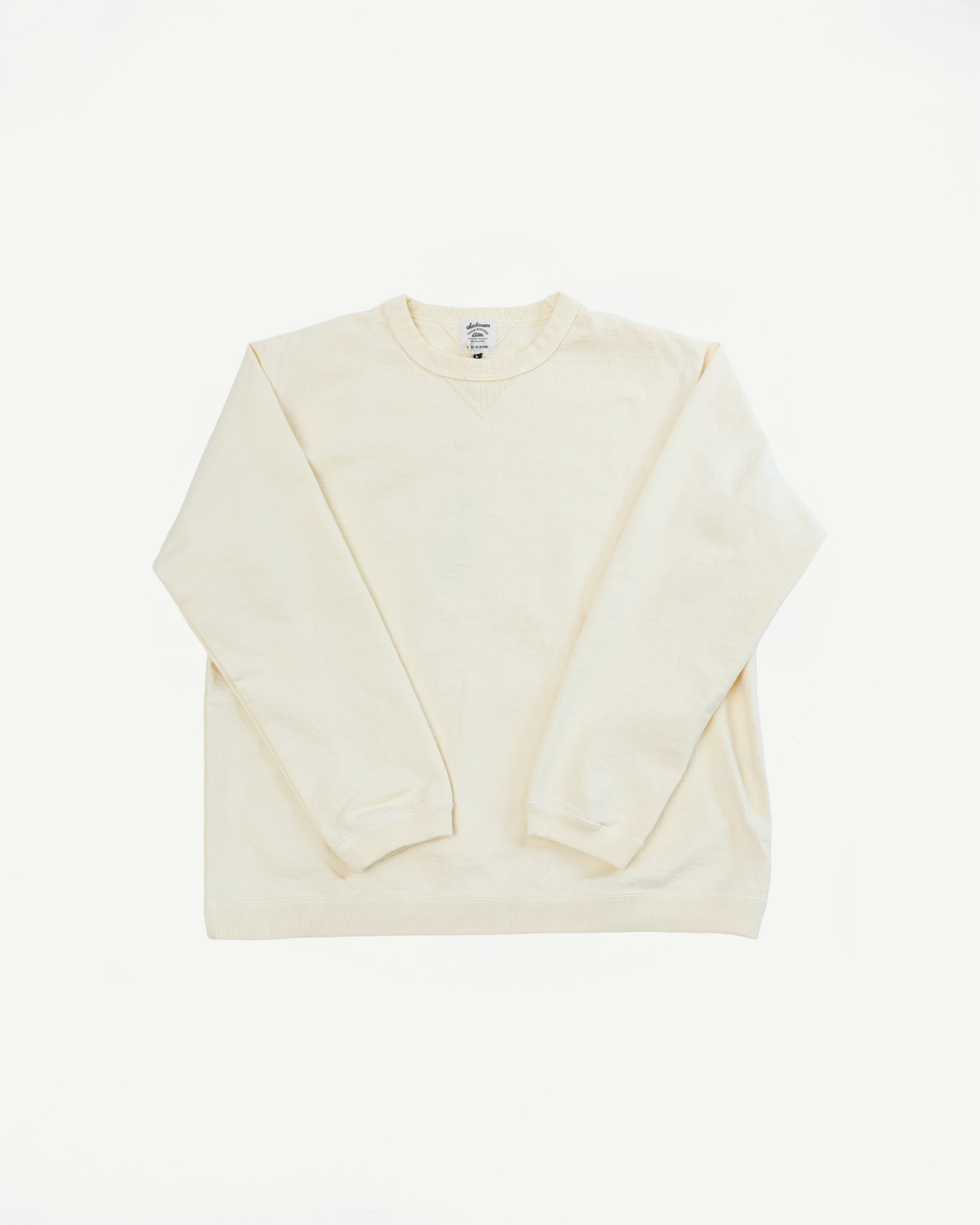 Flat lay of the front of a cream-colored long sleeve crewneck shirt.