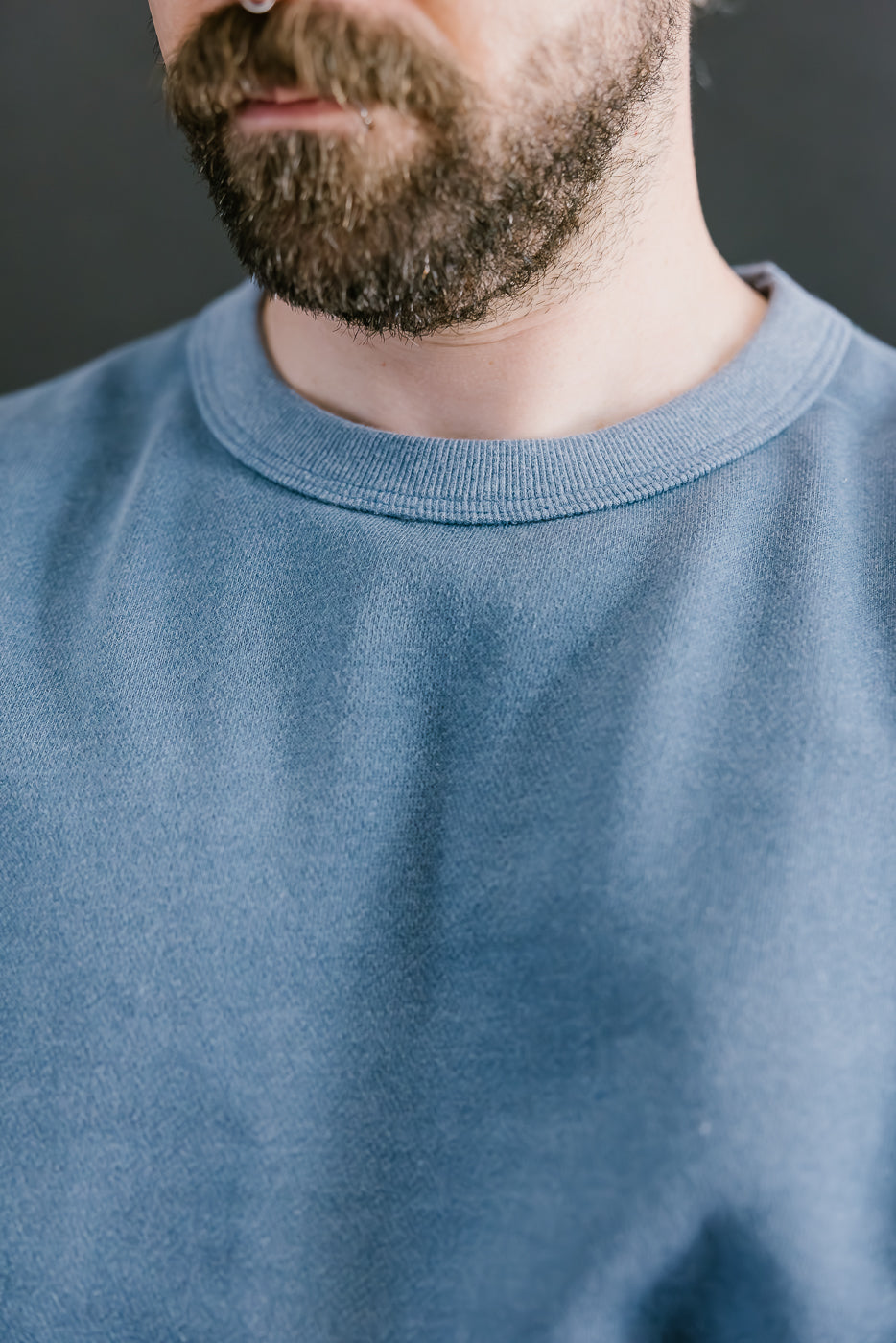 Close-up of a person wearing a blue sweater with a blurred background