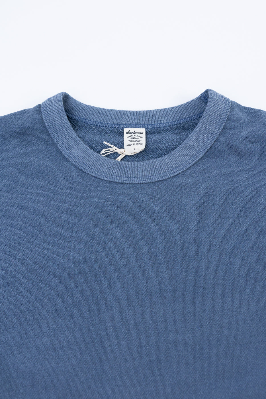 Close-up of a blue shirt with a brand label on a white background