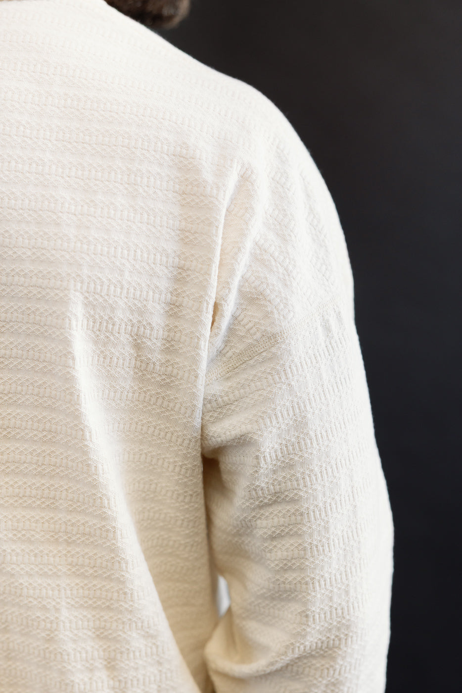 Close-up of men's ecru long sleeve T-shirt back shoulder, textured fabric detail