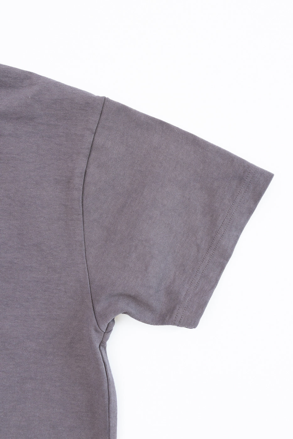 Close-up of gray t-shirt sleeve and shoulder seam, showing fabric texture and stitching detail