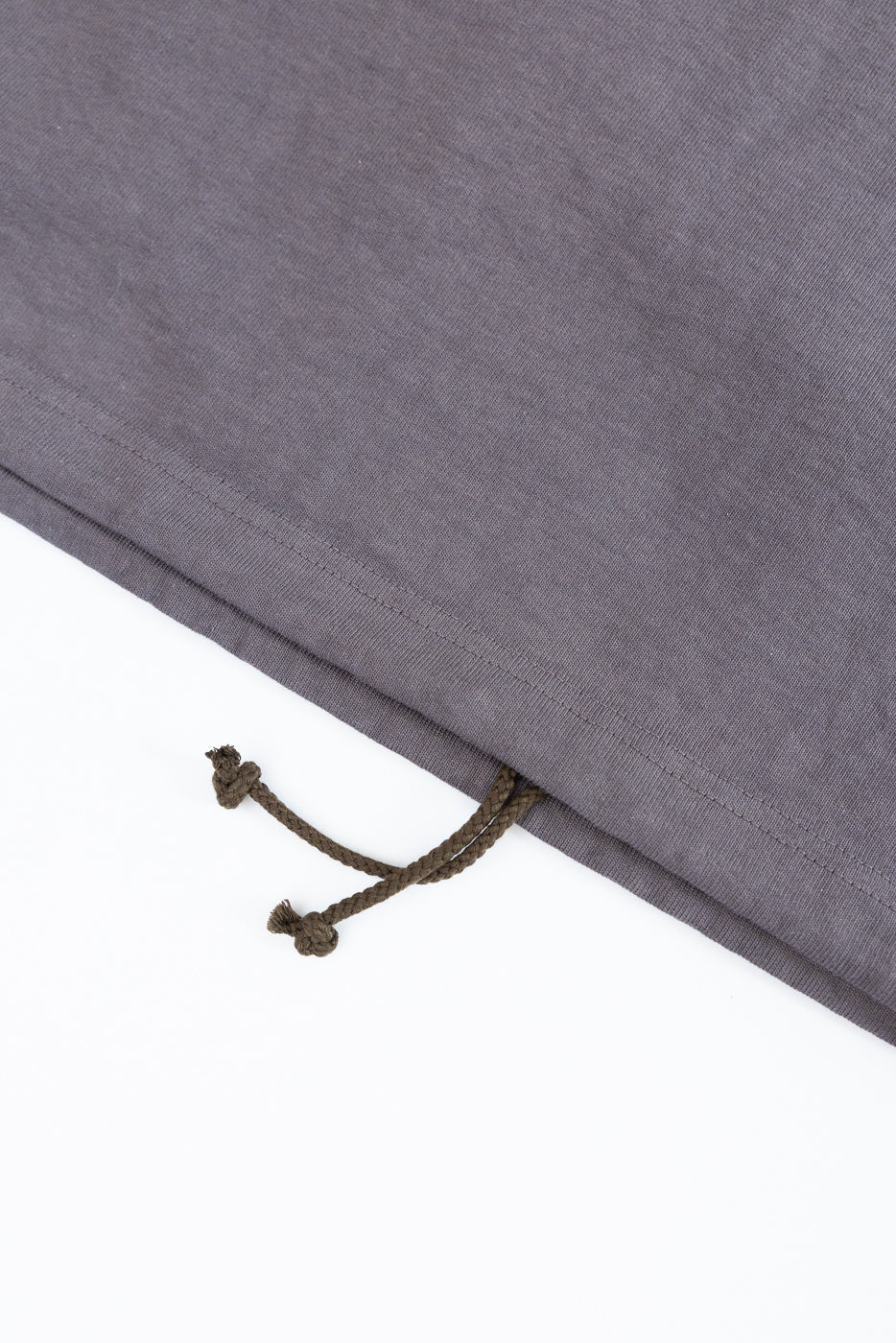 Close-up of gray sweatpants hem with olive drawstring, showing fabric texture and stitching detail